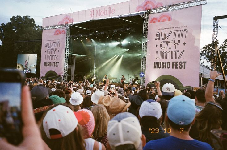 a large group of people standing on top of a stage at an outdoor music festival