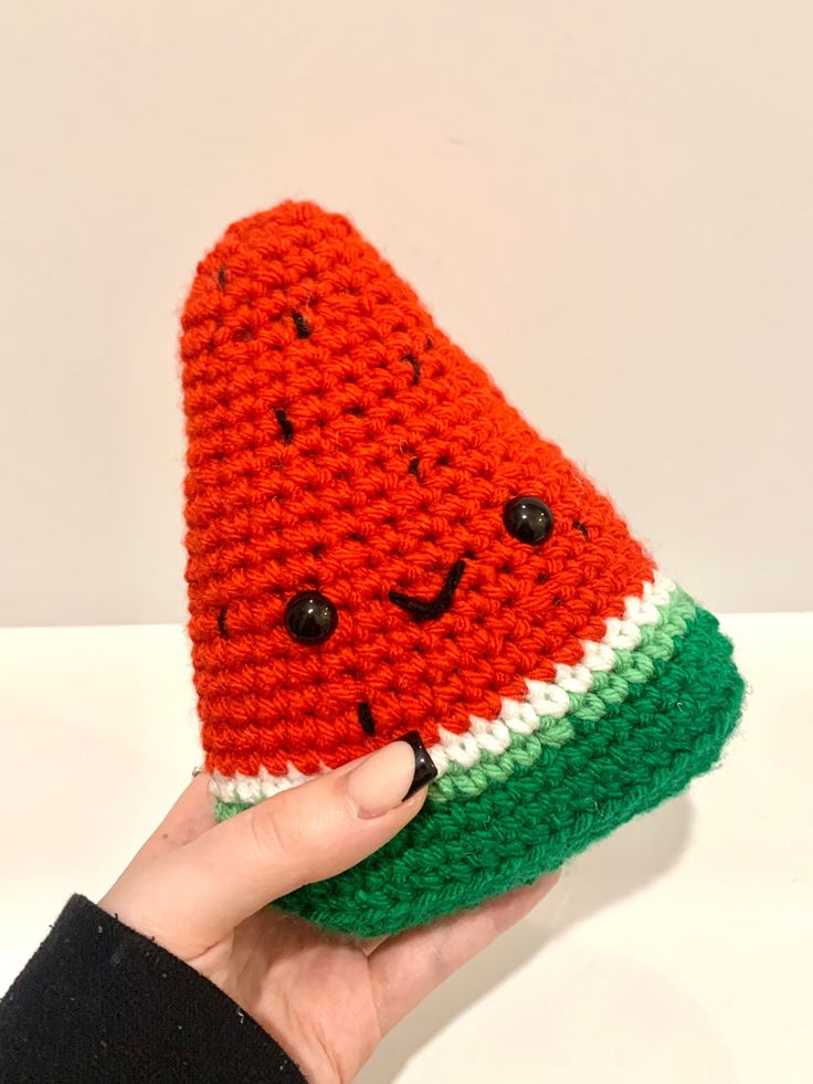 a hand holding a knitted watermelon hat