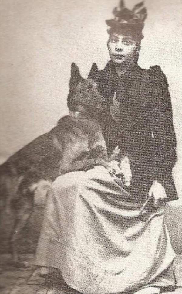 an old black and white photo shows a man in costume with a dog on his lap