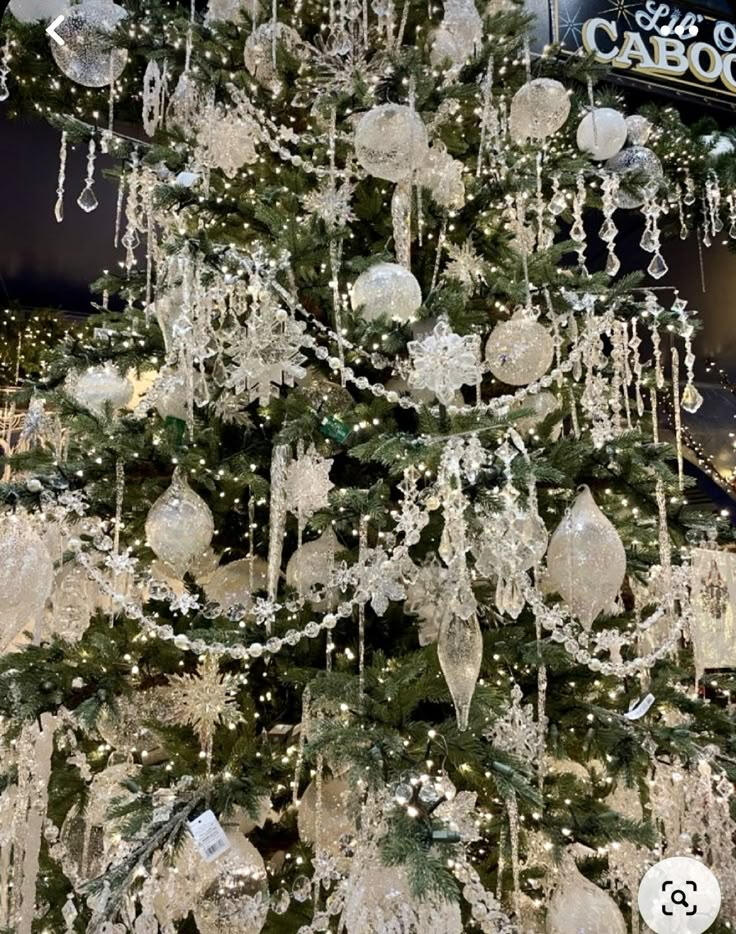 a christmas tree is decorated with white and silver ornaments