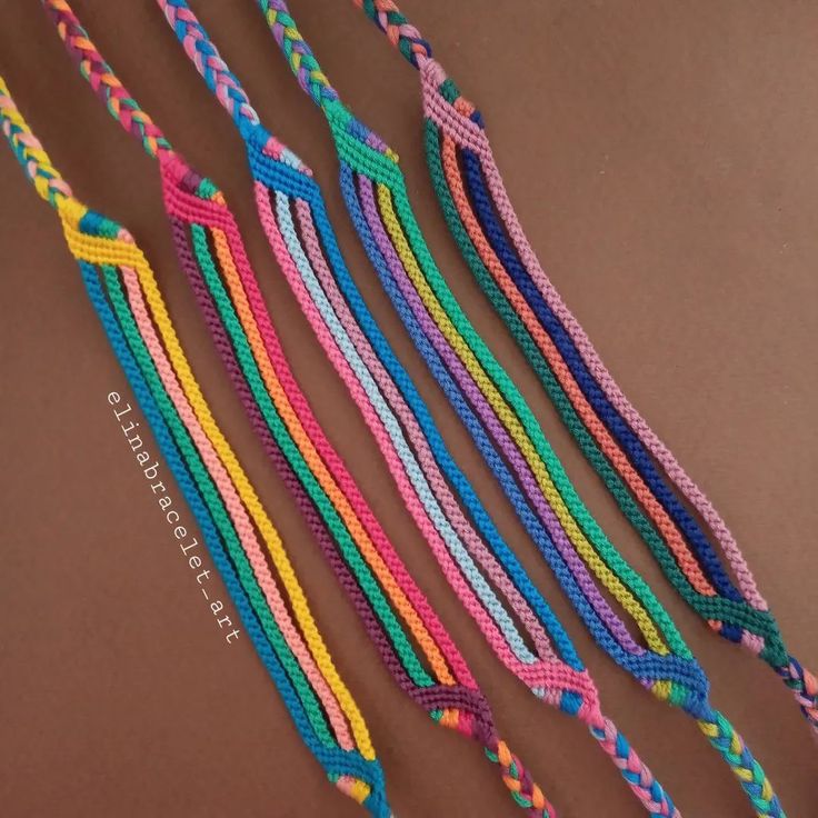 multicolored braided bracelets are laid out on a brown surface