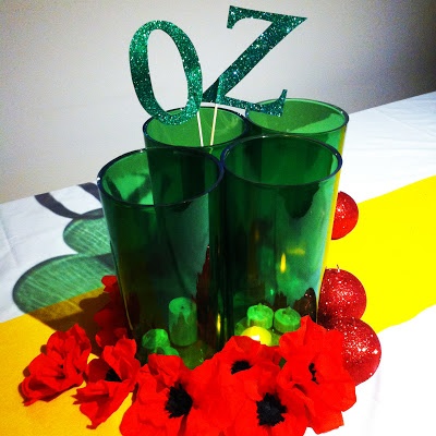 two green glasses sitting next to each other on top of a table with red flowers