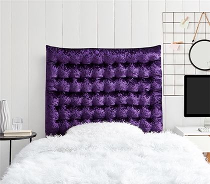 a bedroom with a purple headboard and white fur rugs on the floor next to a computer desk