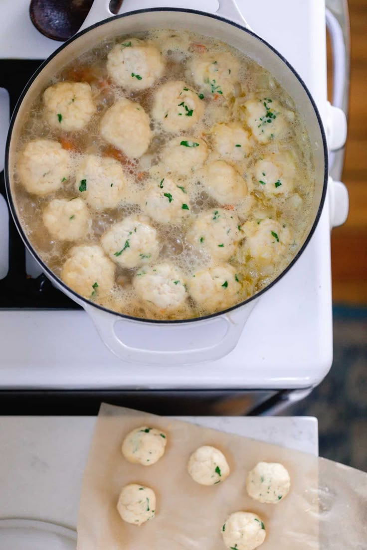 a pot full of food sitting on top of a stove next to a cutting board