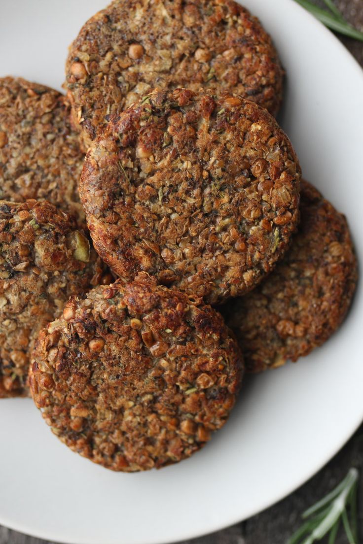 four cookies on a white plate with rosemary sprigs