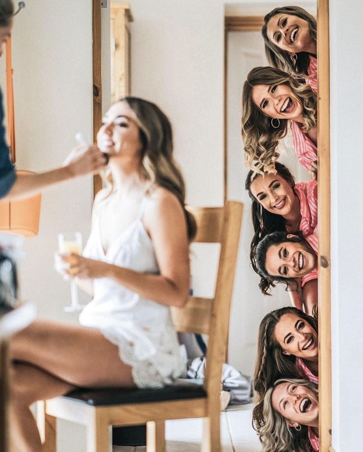 a group of women sitting next to each other on top of a wooden chair in front of a mirror