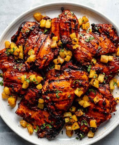 grilled chicken with pineapple salsa on a white platter, ready to be eaten