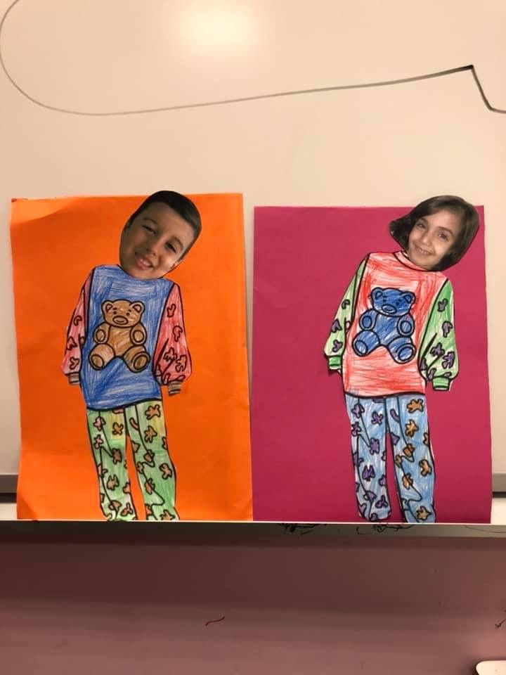 two children's pajamas are on display in front of their paintings, one with a teddy bear