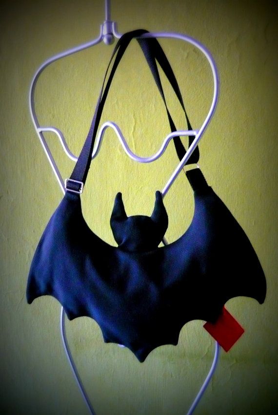 a bat shaped purse hanging from a hook on a yellow wall with a red tag attached to it