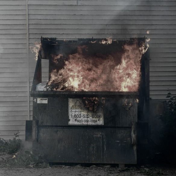 a fire is burning in the back of a dumpster that's on fire