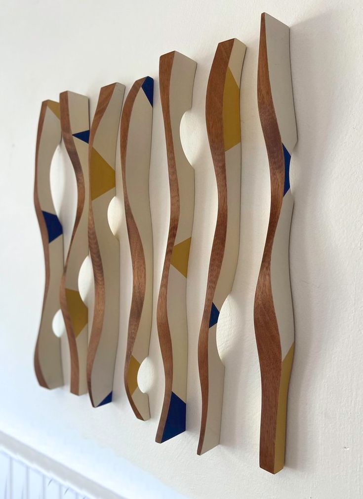 three wooden sculptures hanging on the wall next to a radiator in a room