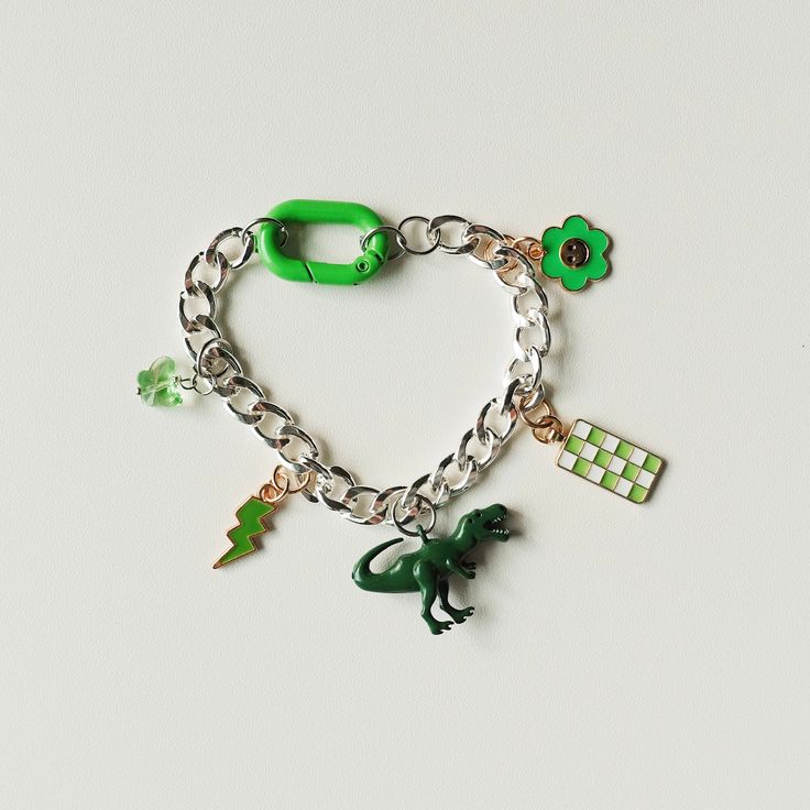 Green: Butterfly, Lightning bolt, Dinosaur, Checkered pendant, flower. Featuring chunky clasp. Trendy Green Jewelry With Flower Charm, Green Metal Charm Bracelet, Jupiter Fl, Green Butterfly, Lightning Bolt, Charm Bracelets, Jewelry Bracelets, Charm Bracelet, Bracelet