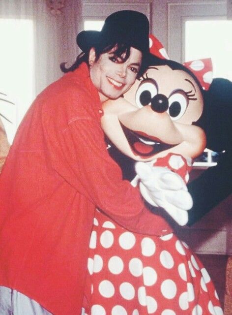 a woman hugging mickey mouse on top of a bed