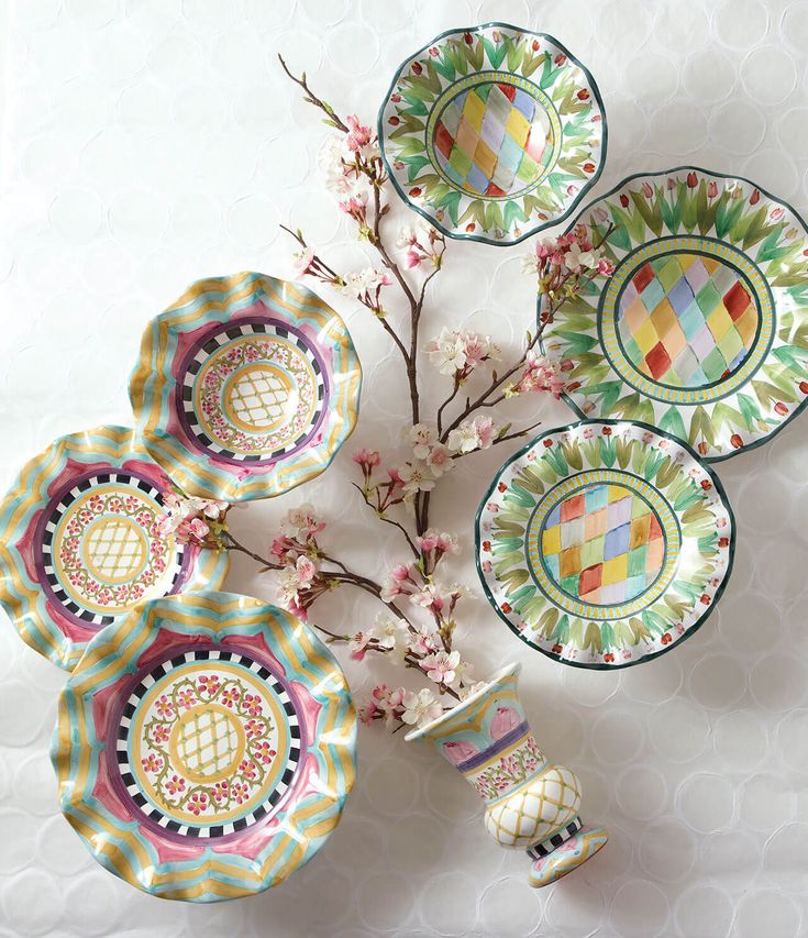 four plates and two vases with flowers in them on a white tablecloth background