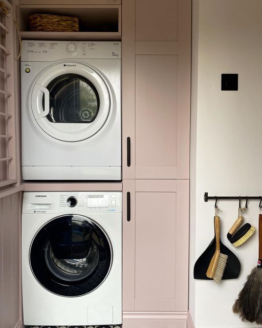 a washer and dryer in a small room with pink cabinets on the wall