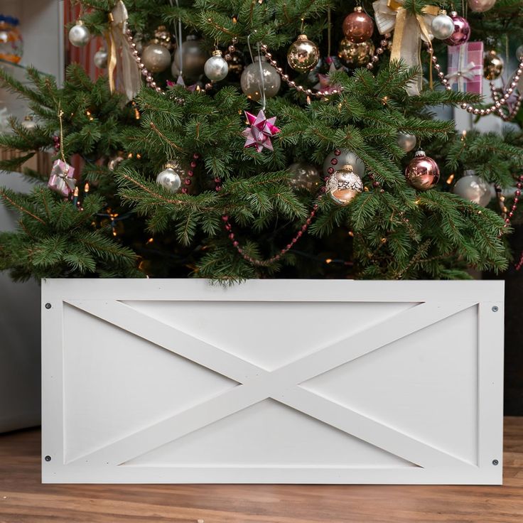 a christmas tree with ornaments hanging from it's branches in front of a white box