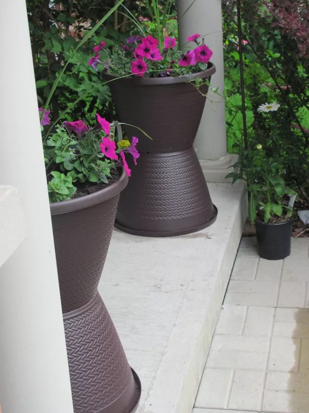 three flower pots sitting on the side of a building with purple flowers growing out of them