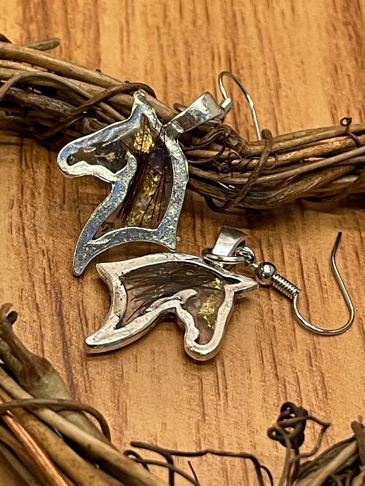 a pair of earrings sitting on top of a piece of wood next to some twigs