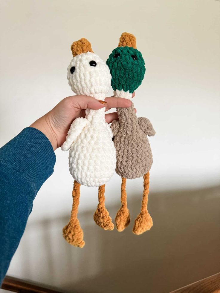 someone is holding two small crocheted animals