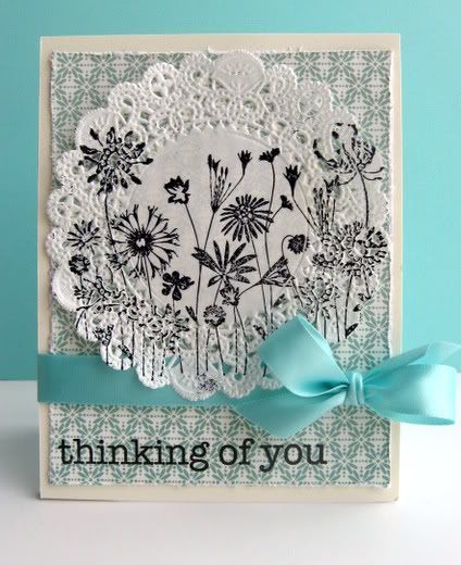 a white card with blue ribbon on it that says thinking of you, and an image of flowers