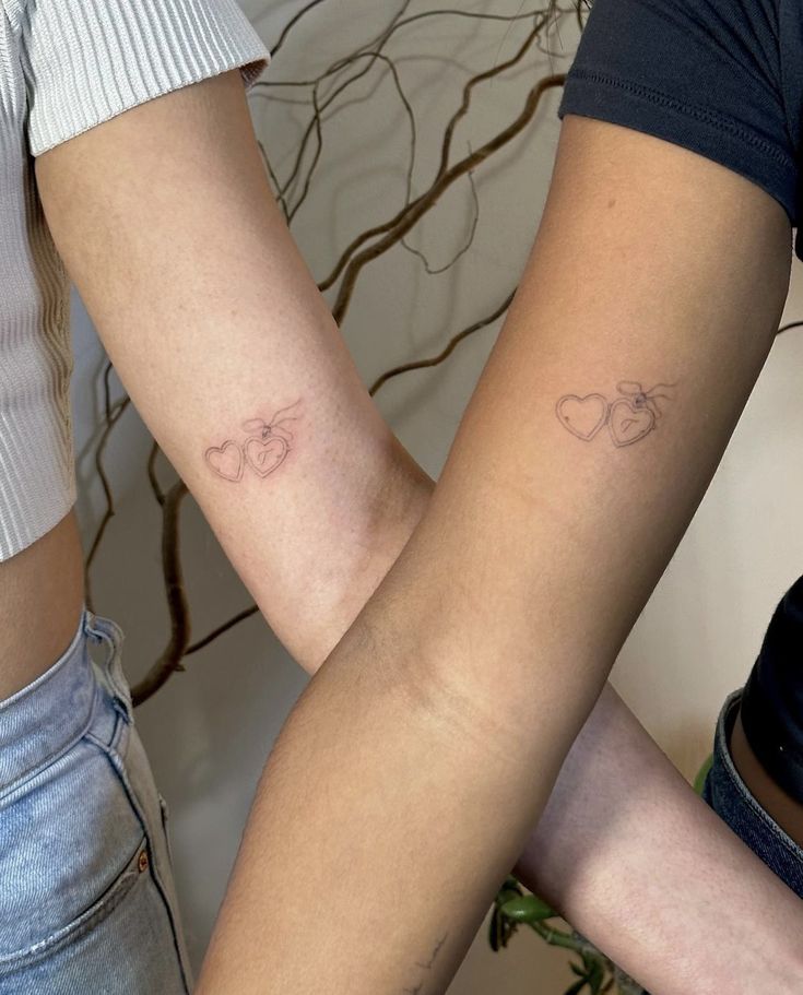 two people with matching tattoos on their arms, one holding the other's arm