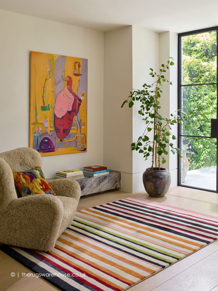 a living room with a rug, chair and potted plant