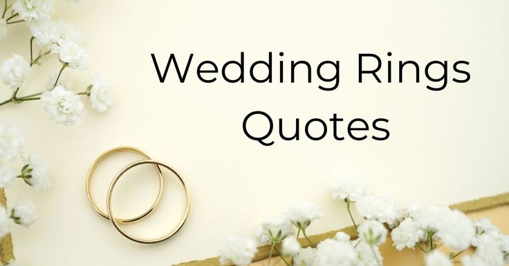 two wedding rings sitting on top of a table next to white flowers and greenery