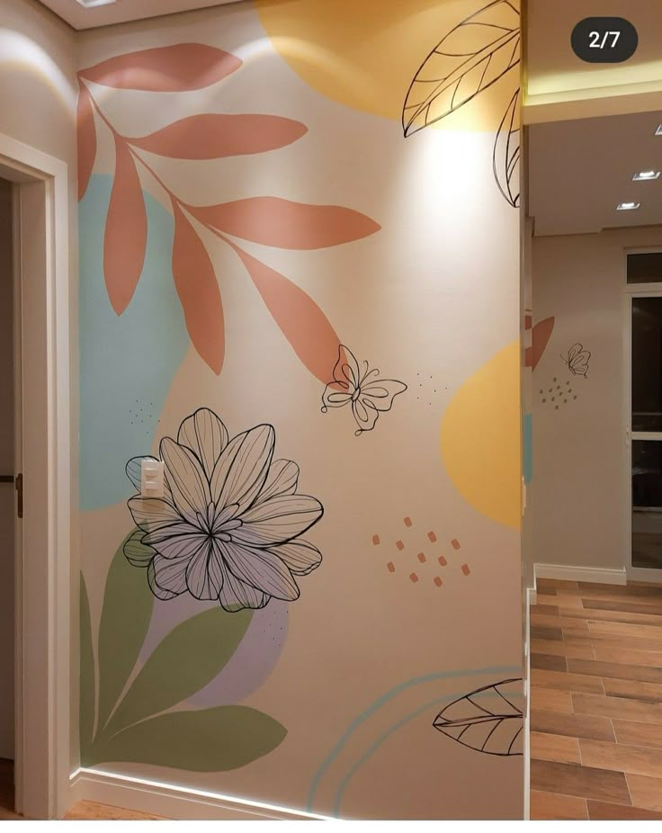 a wall with flowers painted on it in a room that has wooden floors and white walls