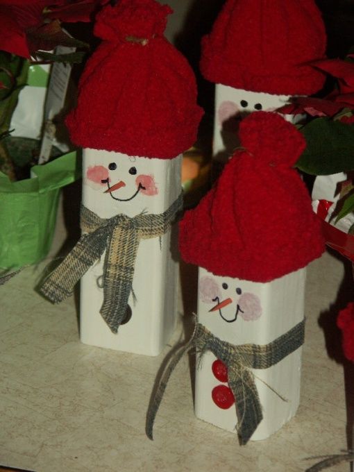 three snowmen made out of wine bottles sitting on a counter next to red flowers