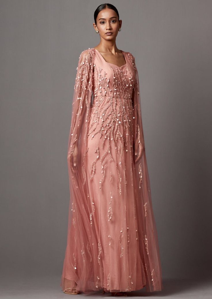 Dusty Rose cape gown in net fabric, it is hand embroidered. Cape is detachable. Floor-length Dresses With Sheer Sleeves For Reception, Pink Wedding Gown With Cape Sleeves, Fitted Hand Embellished Dresses With Cape Sleeves, Hand Embellished Fitted Dress With Cape Sleeves, Hand Embellished Fitted Gown With Cape Sleeves, Pink Gown With Cape Sleeves, Pink Fitted Gown With Cape Sleeves, Elegant Pink Gown With Cape Sleeves, Pink Cape Sleeve Gala Dress