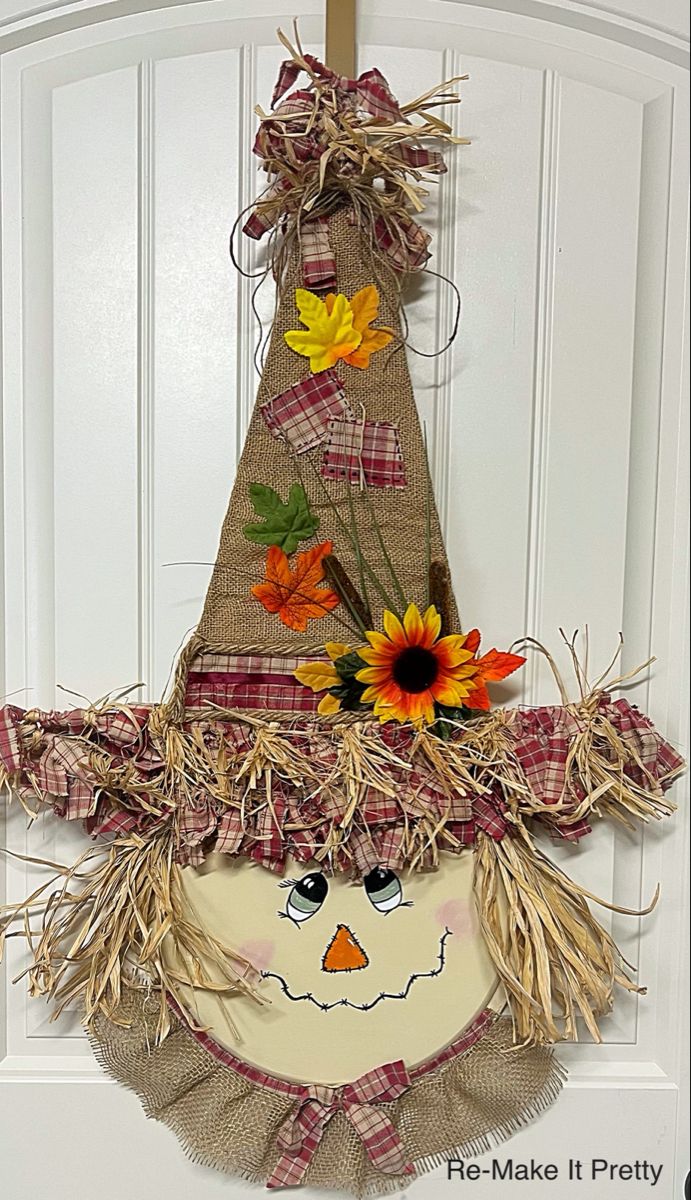 a scarecrow door hanger with sunflowers and leaves on it's head