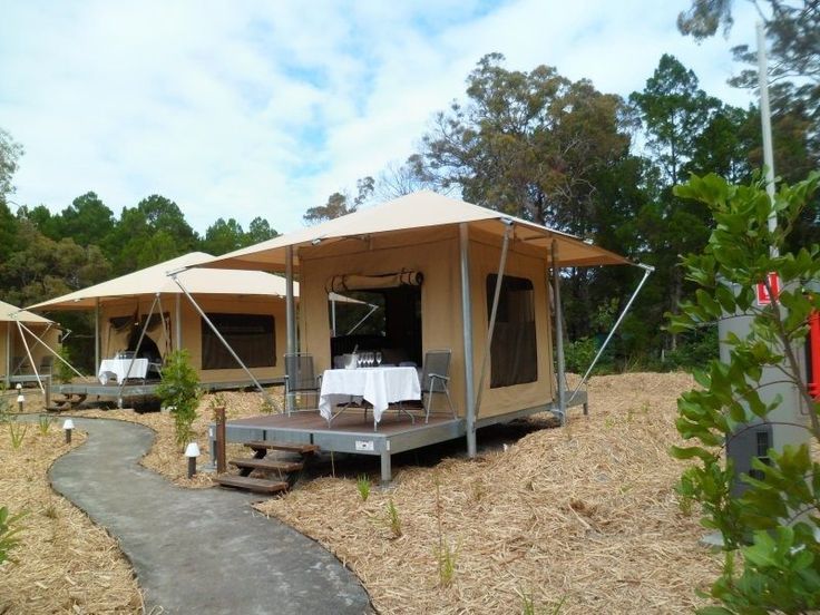 several tents set up in the woods with tables and chairs on top of each tent