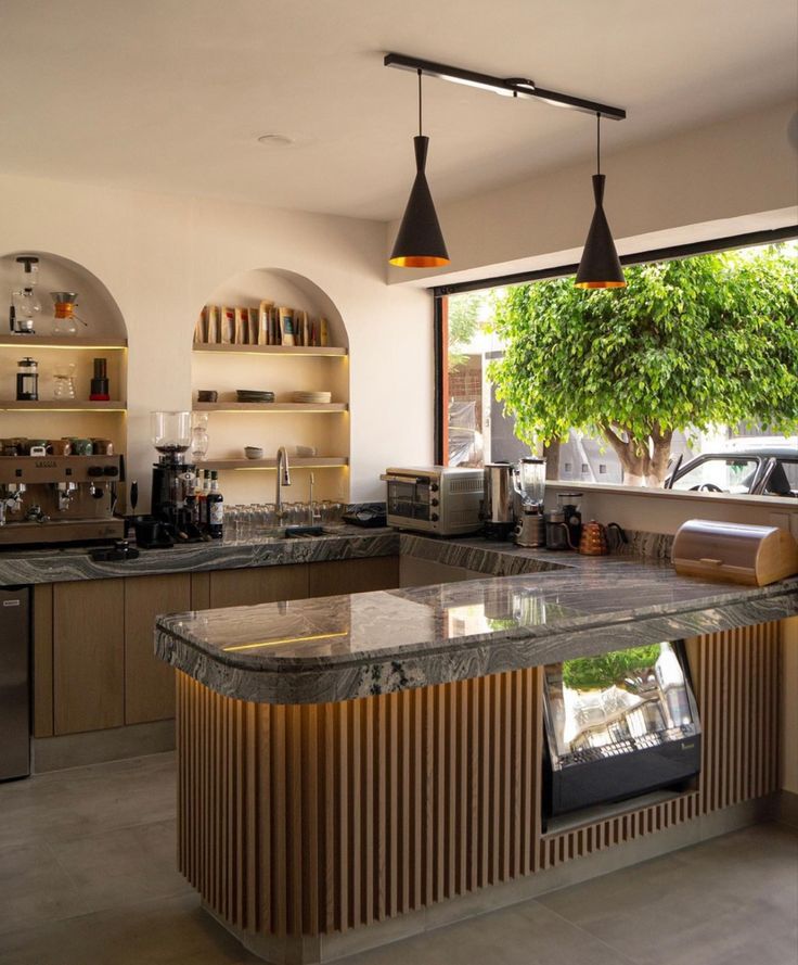 an open kitchen with marble counter tops and stainless steel appliances, along with hanging lights