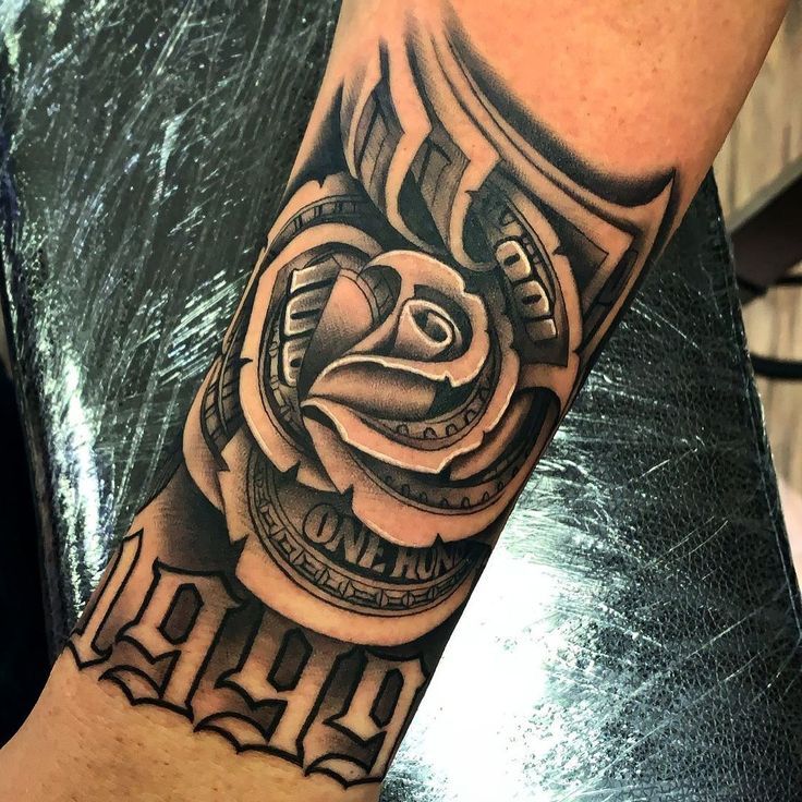 a man's arm with a black and grey tattoo design on it, featuring a rose