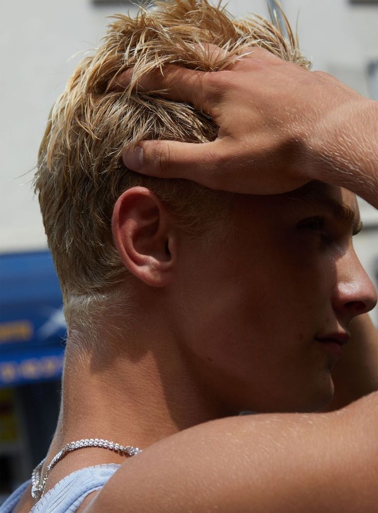 a man with blonde hair is holding his hand to his head