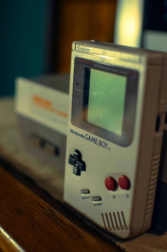 an old gameboy sitting on top of a wooden table