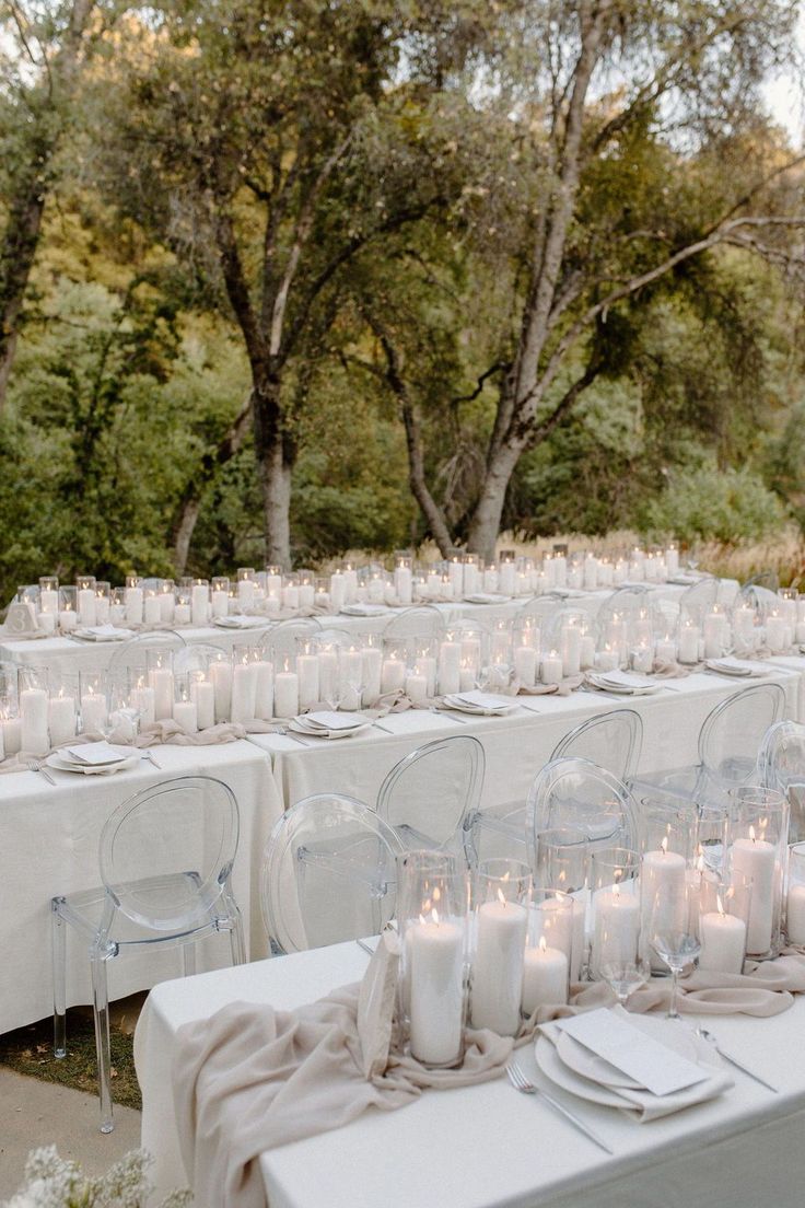 the tables are set up with white linens and lit candles for an outdoor wedding