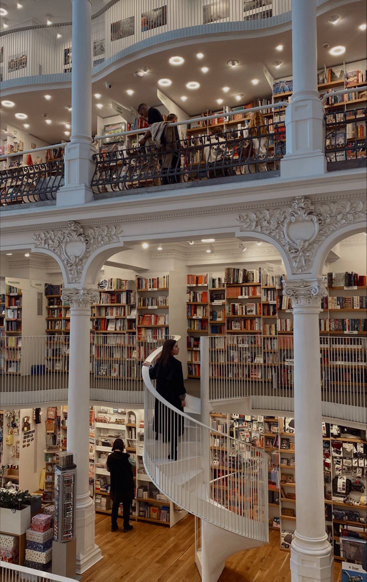 two people are standing on the stairs in a library