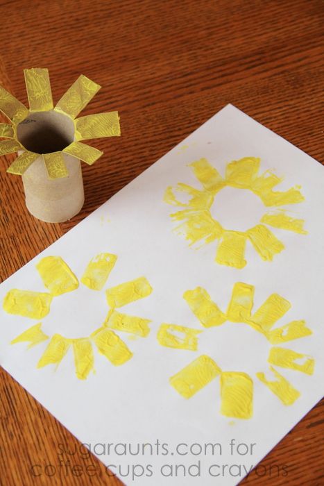 a paper plate with yellow flowers on it next to a crafting roll and glue