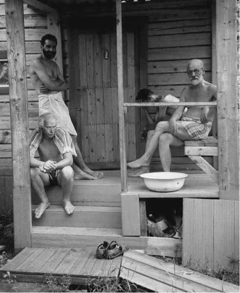 three men sitting on the porch of a cabin