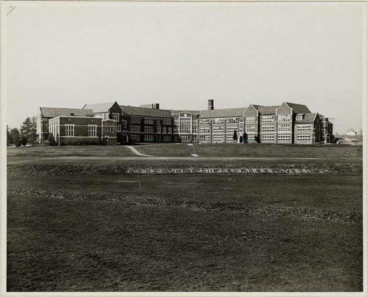 an old black and white photo of a large building in the middle of a field