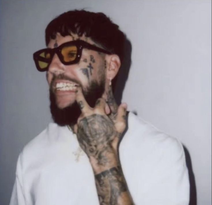 a man with tattoos and sunglasses making the peace sign