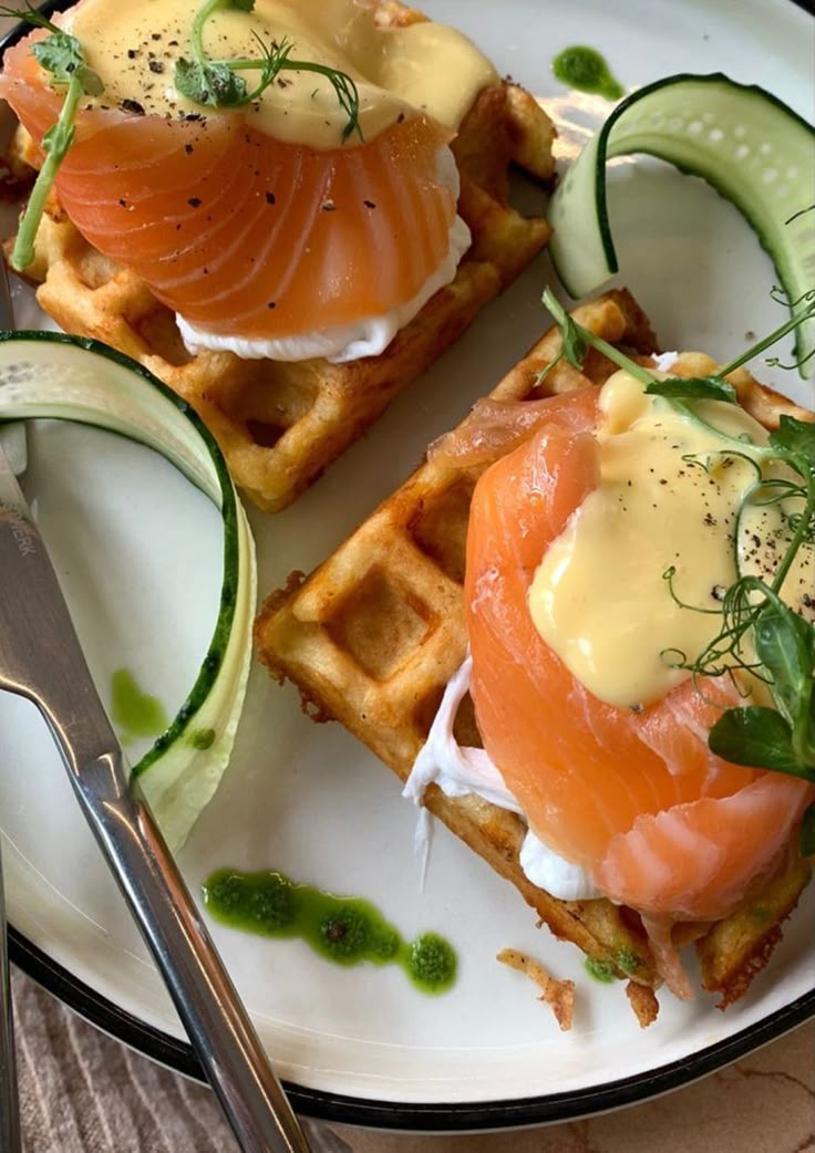 two waffles topped with smoked salmon and cucumber garnish on a white plate