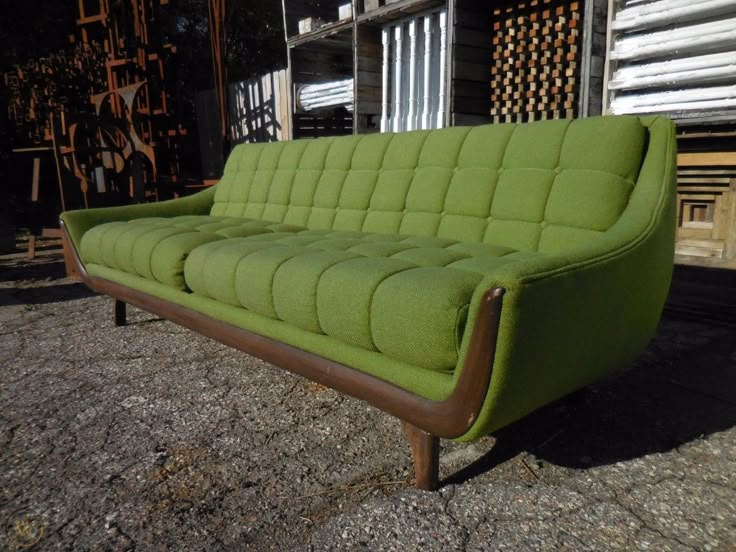 a green couch sitting in front of a building