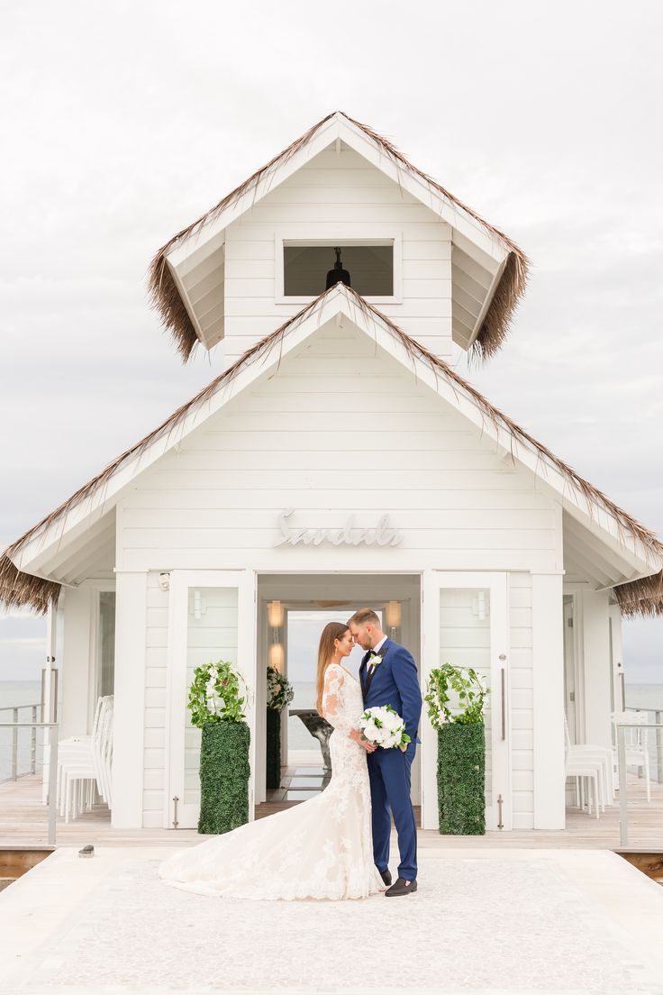 a bride and groom standing in front of a white church