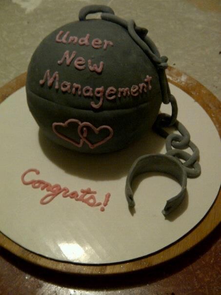 there is a cake that says under new management on the top and below it is a keychain