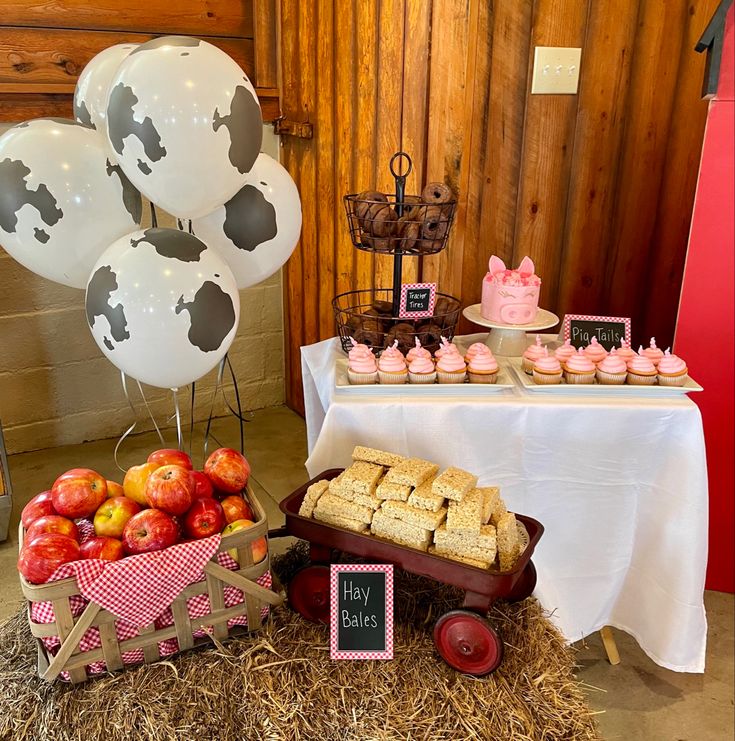 a table topped with lots of desserts and cupcakes on top of hay