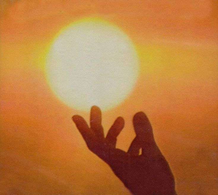 a hand reaching up to the sun with it's fingers in front of it