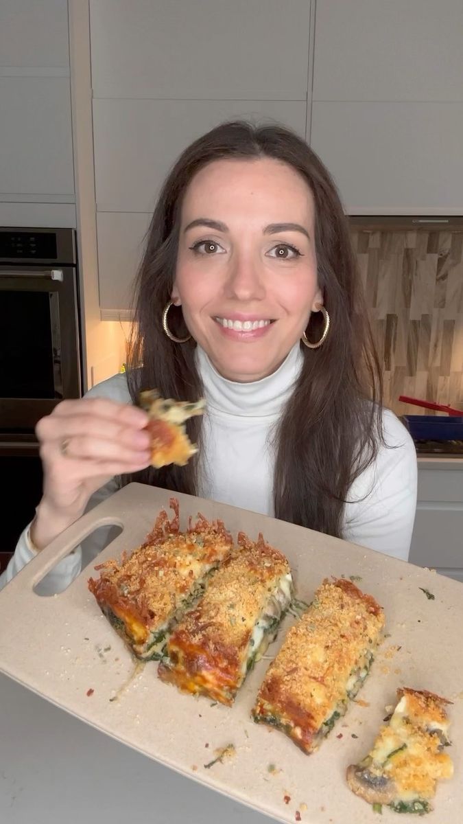 a woman is holding up some food in front of her face and smiling at the camera