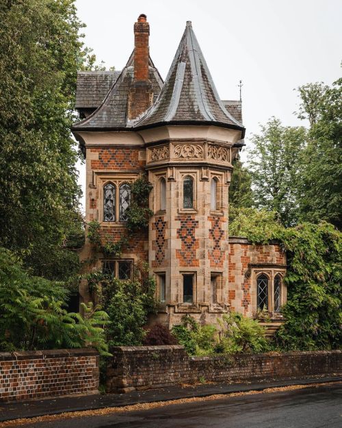 an old brick building with two clocks on it's side and trees in the background